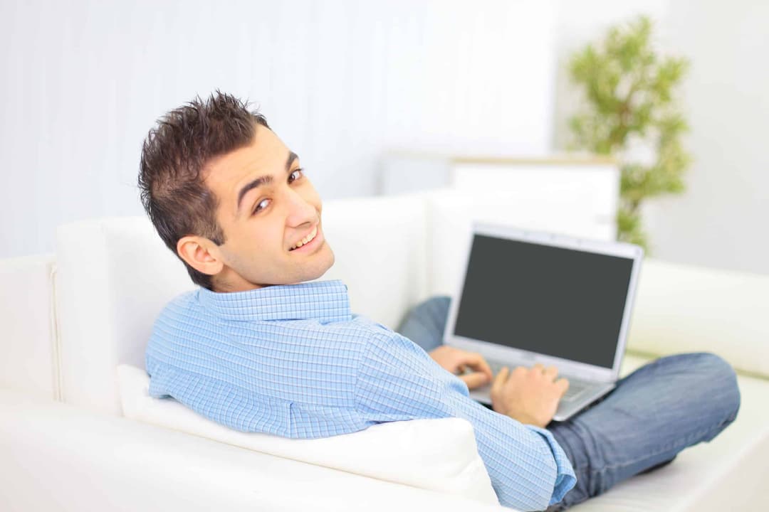 Man met laptop op de bank
